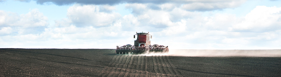 Tractor, land preparation with seed cultivator in farmland. The tractor plows the field. Agricultural works for processing, tillage. Farmers preparing the land and fertilizing. Farmland, tractor with seeder, sowing and fertilizer